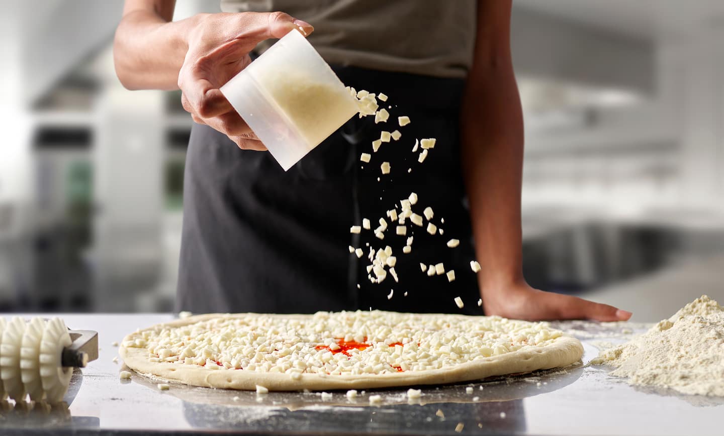 Papa Johns pizza maker adding fresh cheese to a pizza