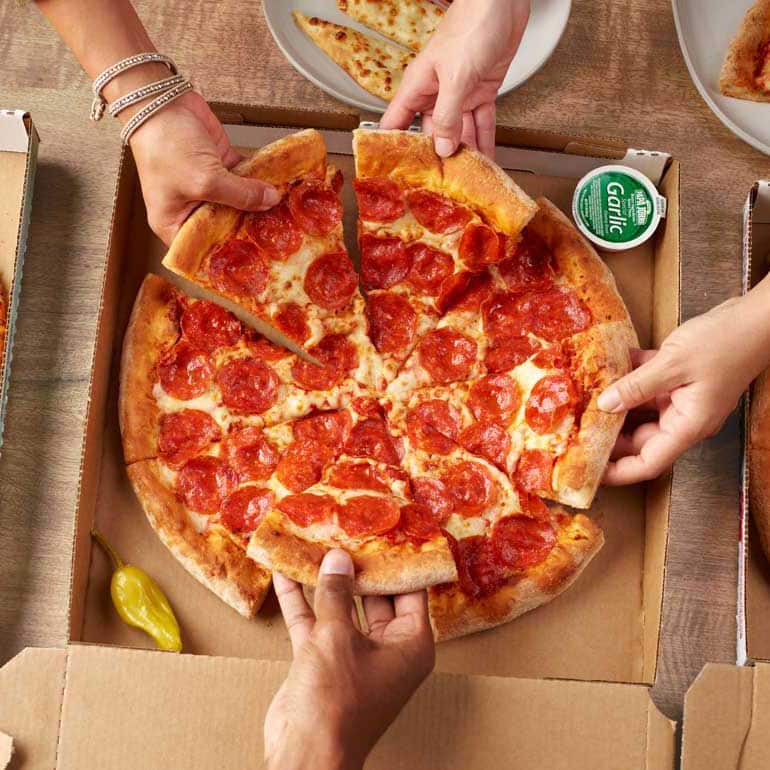 manos compartiendo una pizza de pepperoni