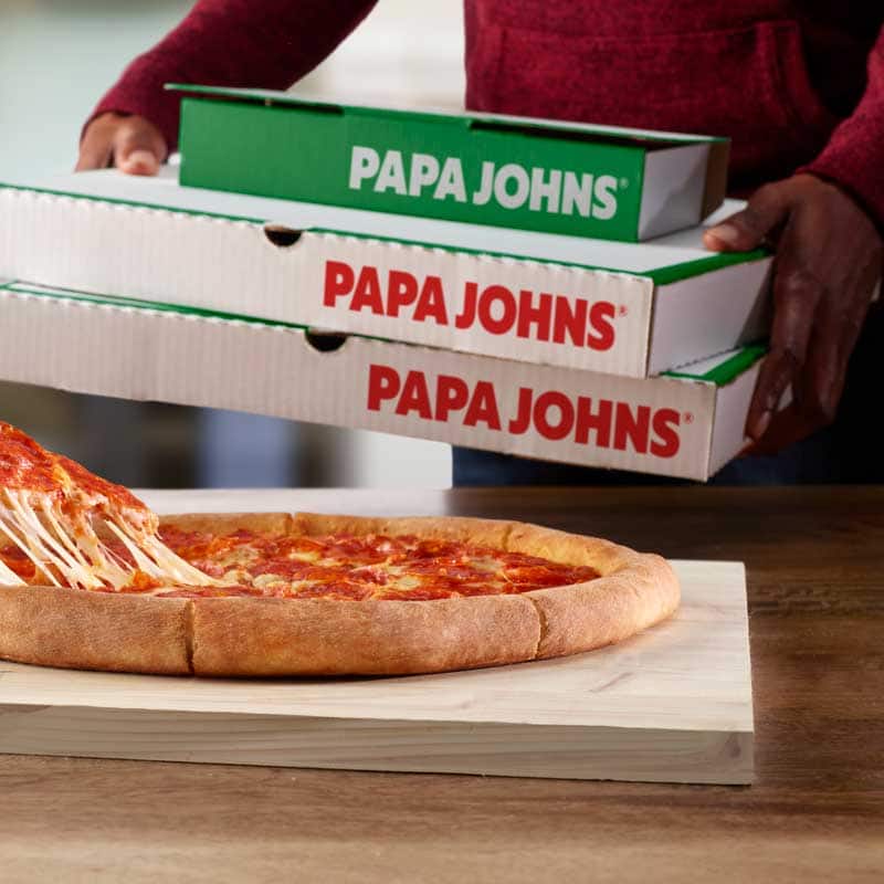 pizza de pepperoni y manos sosteniendo cajas de pizza