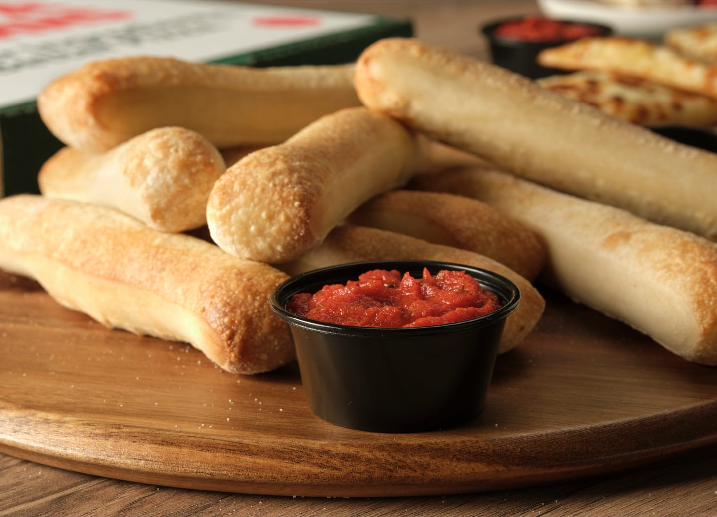 A stack of Papa Johns Breadsticks with dipping sauce.